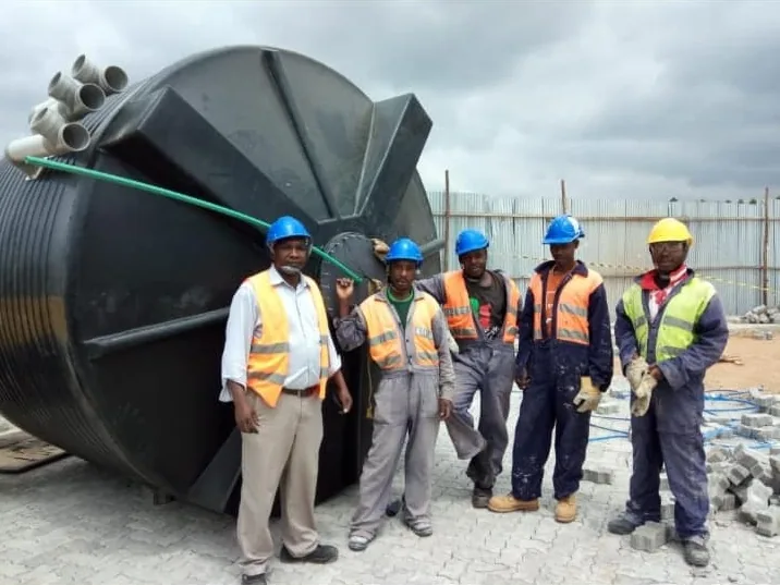 Jobisho installation crew in PPE beside water tanks on site