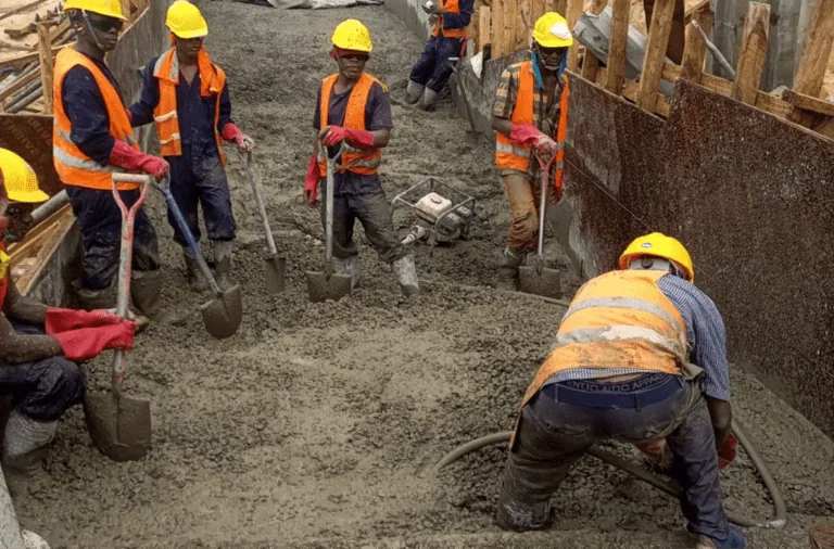 Workers placing concrete in a foundation trench